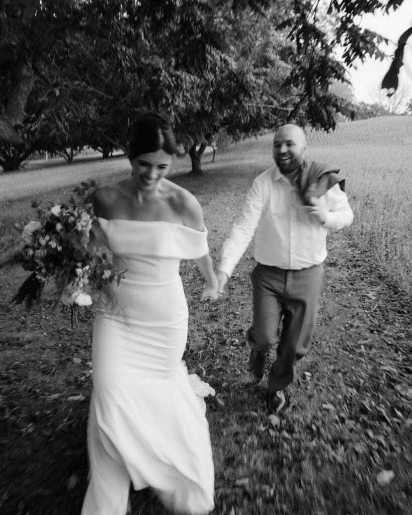 Bride and groom walking across grass at intimate backyard wedding in Brantford, Ontario.