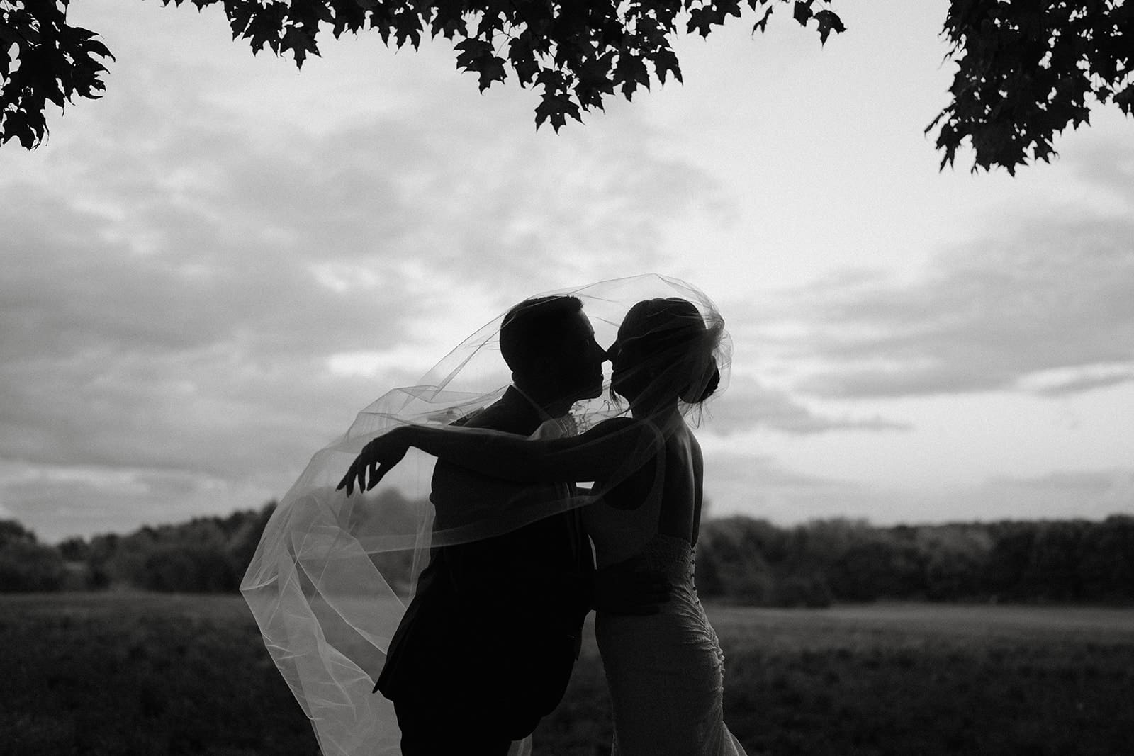 Couple kissing under veil at Brighthouse Farm wedding in Wellington, Ontario.