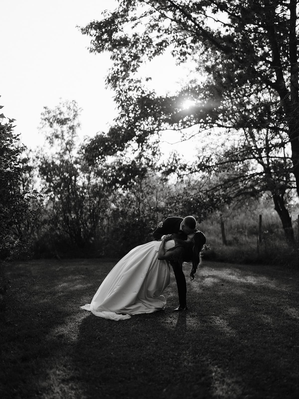 Groom dipping bride at outdoor Eddie Hotel Farm wedding in Bloomfield, Ontario.